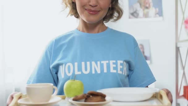 Vrijwilliger bedrijf dienblad met gratis eten, ertoe bijdragen dat mensen met een laag inkomen of dakloos — Stockvideo