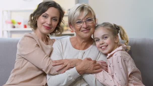Portrét tří generací žen se usmívá na kameru, šťastná rodina pohromadě