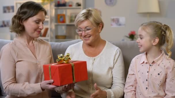 Mère et grand-mère donnant cadeau à l'écolière, encourageant à bien étudier — Video