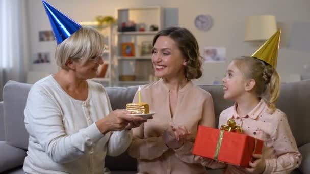 Jeune femme soufflant bougie d'anniversaire, recevant des cadeaux de famille aimante — Video