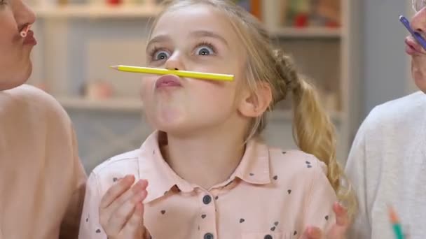Niña haciendo bigote con lápiz, divirtiéndose con los padres, felicidad — Vídeos de Stock