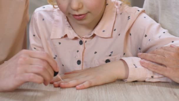 Mãe cuidadosamente pintar unhas filha, uso de ensino cosméticos, salão de beleza — Vídeo de Stock