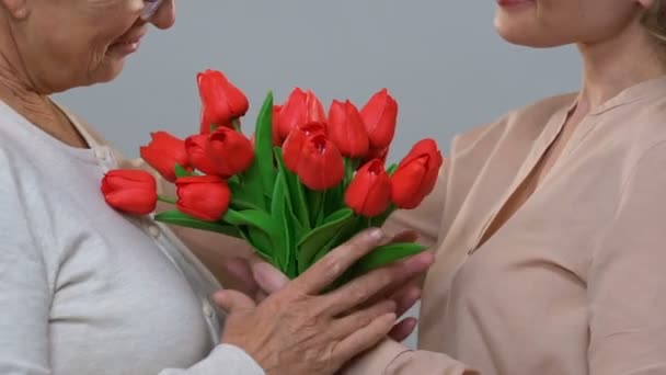 Hija adulta dando flores a mamá mayor, respeto por la generación mayor — Vídeos de Stock