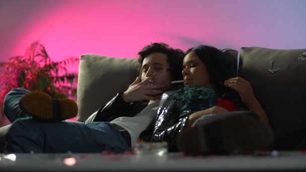 П'яна пара палить сигарети на дивані нічного клубу, дівчина похмілля відчуває себе хворим — стокове відео