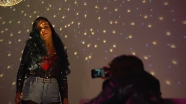 Sexy chica bailando en fiesta rave en las luces del club, hombre filmando vídeo en el teléfono inteligente — Vídeos de Stock
