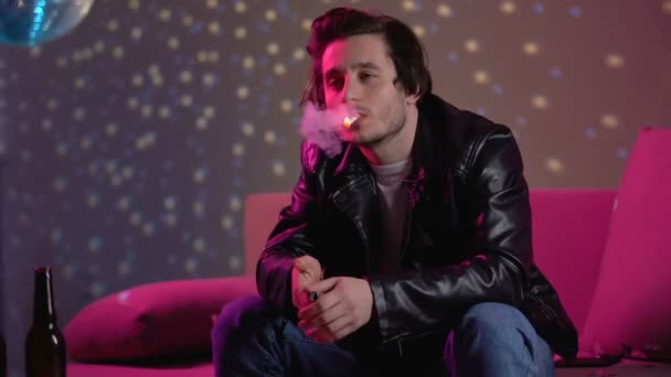 Розслаблений чоловік палить сигарету, охолоджується на приватній вечірці диско, дозвілля — стокове відео