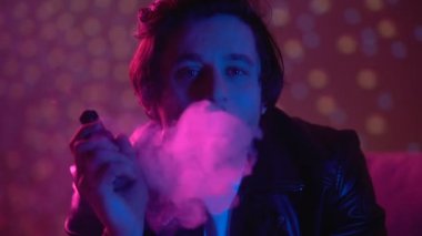 Düşünceli mutsuz adam vaping e-sigara, gece kulübü ışıklar duman exhaling