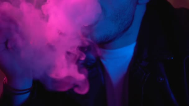 Cigarrillo electrónico de vapeo criminal masculino y humo exhalador en la oscuridad del club nocturno — Vídeos de Stock