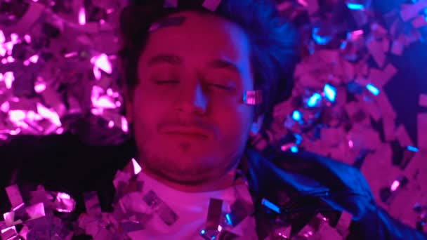 Несвідомий наркоман прокидається на підлозі нічного клубу, конфетті падає, вид зверху — стокове відео