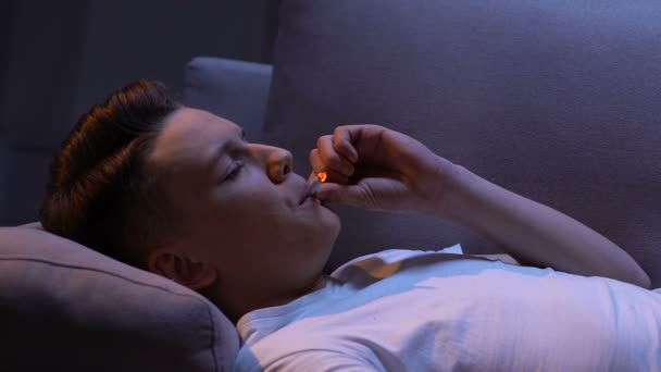Депрессивный подросток пытается курить сигарету, вдыхает дым и кашель, проблема — стоковое видео