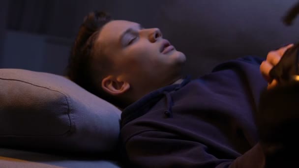 Уставший молодой человек падает на кровать, уставший после дополнительного рабочего времени, спит — стоковое видео