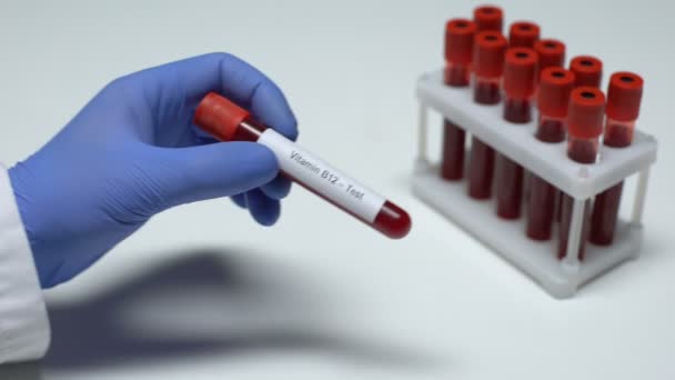 Vitamine B12, médecin montrant un échantillon de sang dans un tube, recherche en laboratoire, bilan de santé — Video