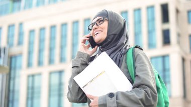 Neşeli Arapça kız öğrenci telefon ayakta Üniversitesi kampüsünde konuşurken