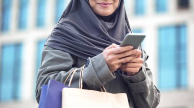 Gülümseyen Arapça Bayan açık havada alışveriş tutan telefonda Sohbet çanta, Gadget'ı