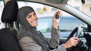 Arabanın anahtarını kamera gösterilen, yeni otomatik sürücü belgesi satın alma hijab gülümseyen kadın