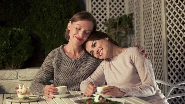 愉快的女士拥抱最好的朋友 坐在咖啡馆的露台上 有愉快的谈话 — 图库照片