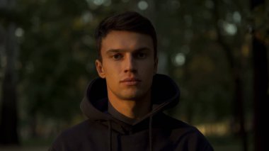 Genç adam kameraya bakarak, yarı gölgeli yüzü, iyi ve kötü mücadele kavramı