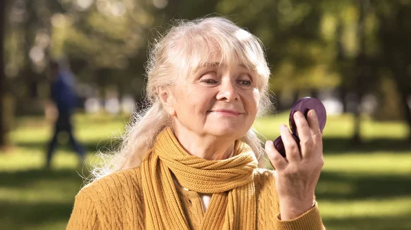 Moden Kvinde Ser Hendes Refleksion Kompakt Spejl Sidder Parken - Stock-foto