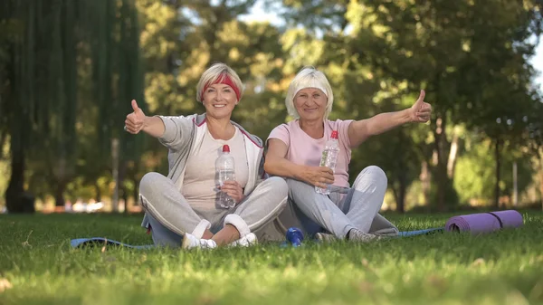 Two Women Showing Thumbs Sitting Grass Doing Exercises Positive — Stock Photo, Image