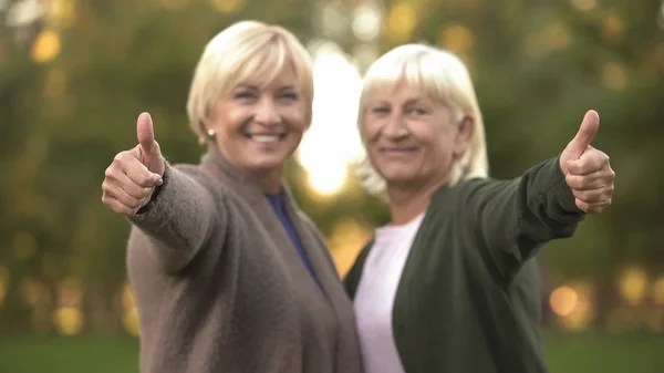 Улыбающиеся Пожилые Женщины Показывающие Большой Палец Вверх Обнимающие Отдыхающие Парке — стоковое фото