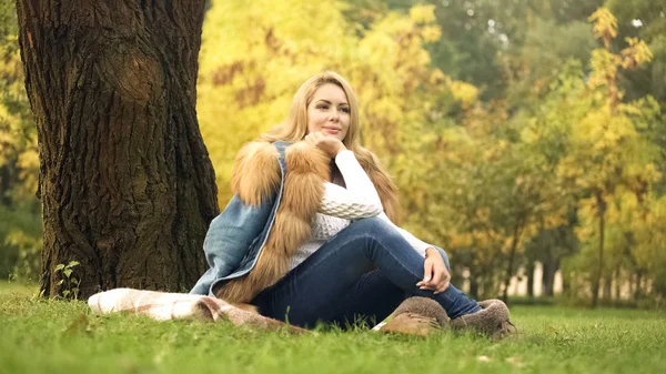 在秋天的公园里 坐在树下的格子上 摆姿势拍照的漂亮女人 — 图库照片
