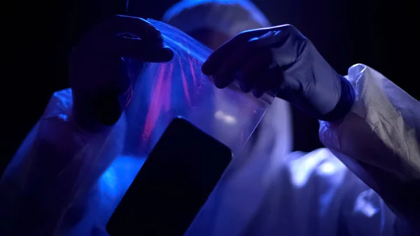 ビニール袋で犯罪者の指紋を持つスマート フォンを置く犯罪の専門家 — ストック写真