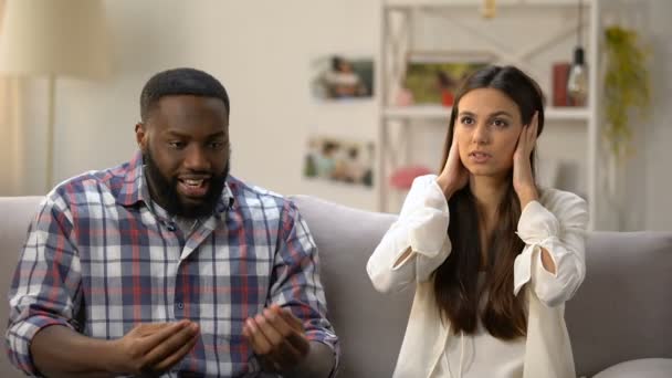 Young lady closing ears with hands, ignoring her black boyfriend talk, quarrel — Stock Video