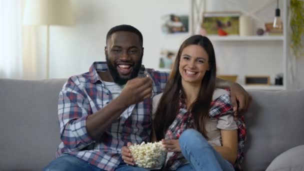 Bonita pareja multiétnica con maíz pop viendo programa de comedia y riendo, relajarse — Vídeo de stock