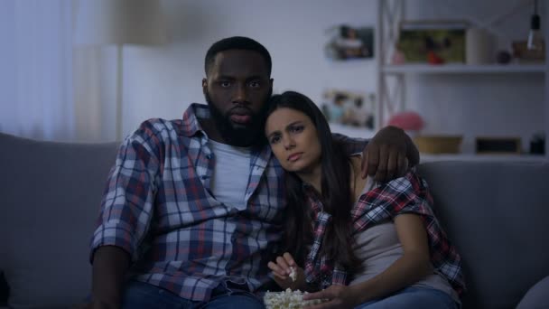 Emotionele mixed-race paar met pop maïs kijken horrorfilm, 's avonds thuis — Stockvideo