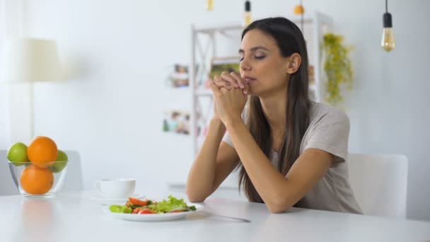 Mladá žena modlí se, požehnaná Bohu za večeři, pojídáním zdravého vegetariánského salátu — Stock video