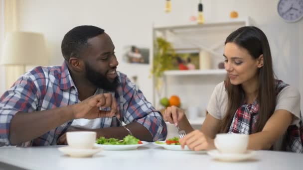 Pareja joven de raza mixta comiendo ensalada, alimentándose mutuamente, relaciones románticas — Vídeo de stock