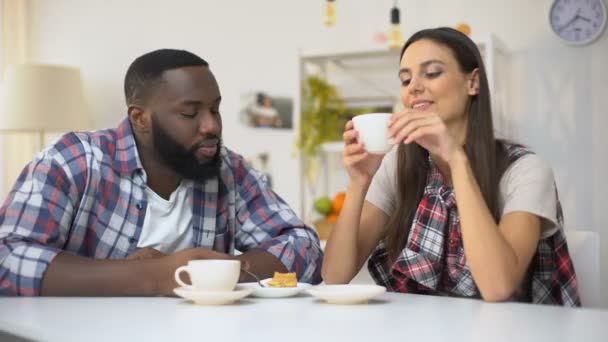 Jovem casal misto comendo deserto, mulher limpando creme de lábios namorado — Vídeo de Stock