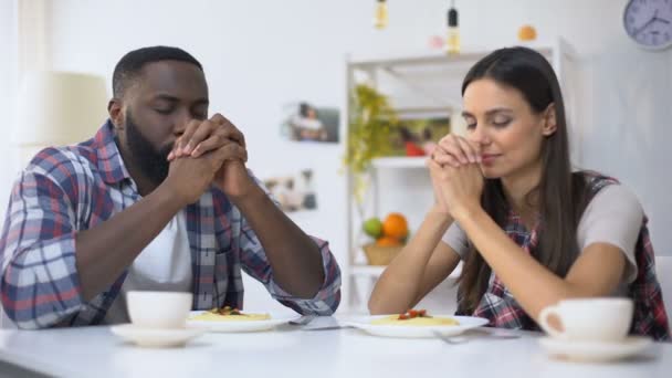 Pareja joven multiétnica rezando antes del almuerzo, agradeciendo a Dios por la comida, la religión — Vídeo de stock