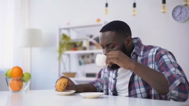 Homme noir manger croissant avec du café, sentir mal aux dents de la nourriture sucrée — Video