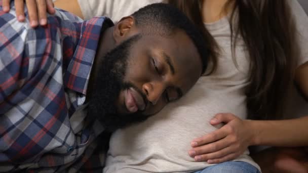 Vrolijke zwarte man praten met zijn zwangere vrouw buik, baby verwachting, familie — Stockvideo
