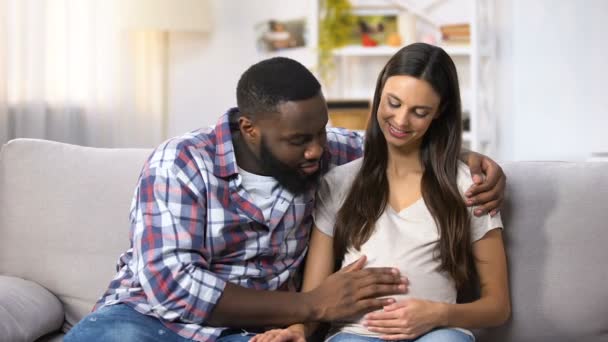 Sonriente hombre afroamericano acariciando su vientre de esposa embarazada, futuros padres — Vídeos de Stock