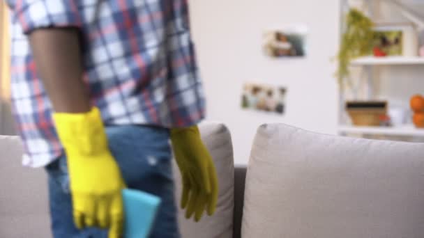 Uitgeput zwarte man in handschoenen zittend op sofa, ontspannen na huis schoonmaken — Stockvideo