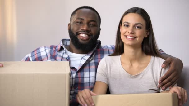 Happy mixed-race paar Holding kartonnen dozen, klaar om te verhuizen in nieuw appartement — Stockvideo