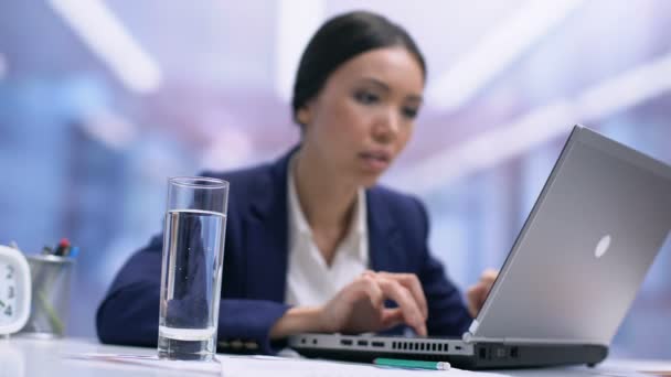 Ocupado empregado do sexo feminino água potável de vidro sentado mesa de escritório, refresco — Vídeo de Stock