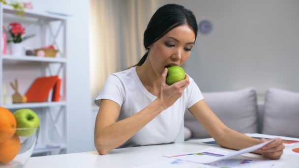 Diseñadora femenina trabajando en casa sintiendo dolor dental mientras muerde manzana fresca — Vídeo de stock