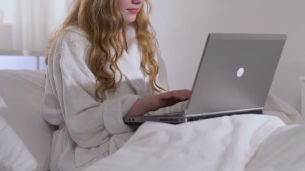 Lady in bathrobe typing on laptop, relaxing at home after workday, chatting — Stock Video