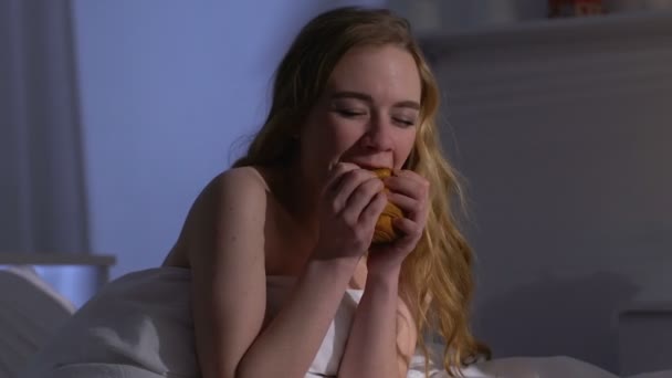 Junge Frau, die nachts gierig Croissant im Bett isst, Bulimie, Hunger — Stockvideo