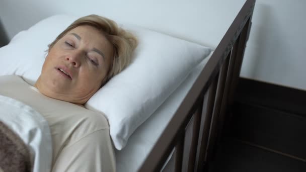 Menina sênior perturbada deitada na cama do hospital, tocando a testa com a mão trêmula — Vídeo de Stock