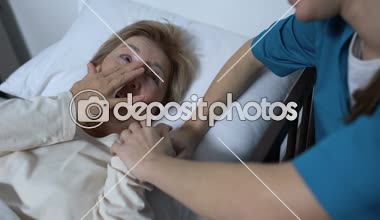 Bakıcı hemşire yaşlı kadın hasta için hasta yatağı rehabilitasyon yalan şakalar söylüyor