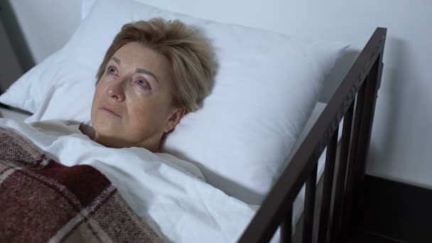 Зріла жінка лежить у лікарняному ліжку, стурбована невиліковною хворобою здоров'я — стокове відео