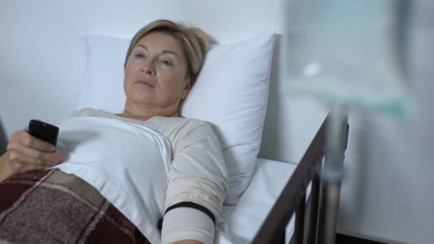 Paciente anciana débil viendo televisión en la sala del hospital, durmiendo en la cama enferma — Vídeos de Stock