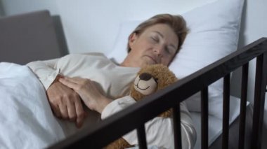 Bakıcı hemşire battaniye ile Teddy-Bear ile uyuyan kadın hasta kapsayan