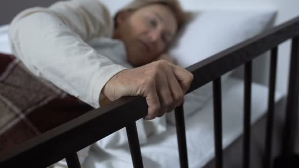 Leeftijd zieke vrouw nauwelijks uit bed vasthouden aan railing, ziekenhuis Ward — Stockvideo