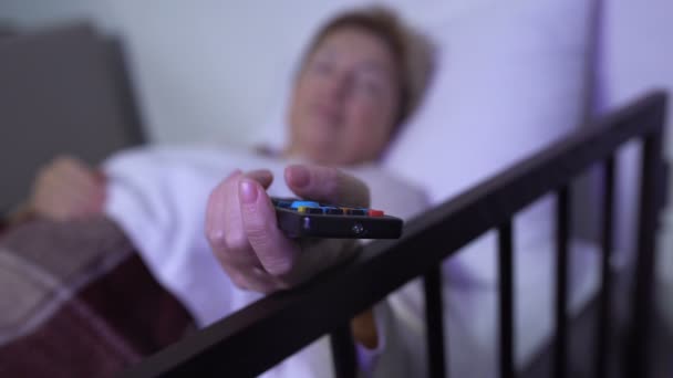 Жінка-пацієнтка засинає з телевізором, доглядаючий медсестра прикриває її ковдрою — стокове відео
