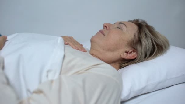 Больной женщиной, страдающей от лихорадки и бреда, медсестрой, надевающей компресс на лоб — стоковое видео
